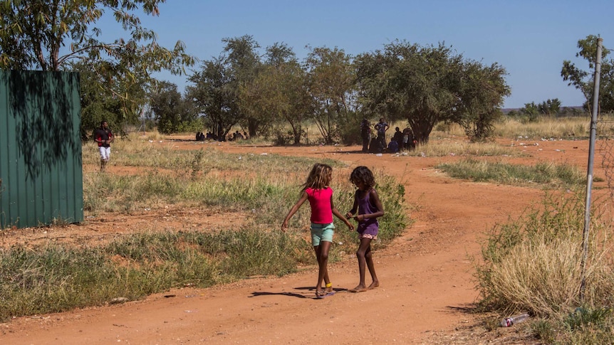 The back streets of Fitzroy Crossing with two girls walking along