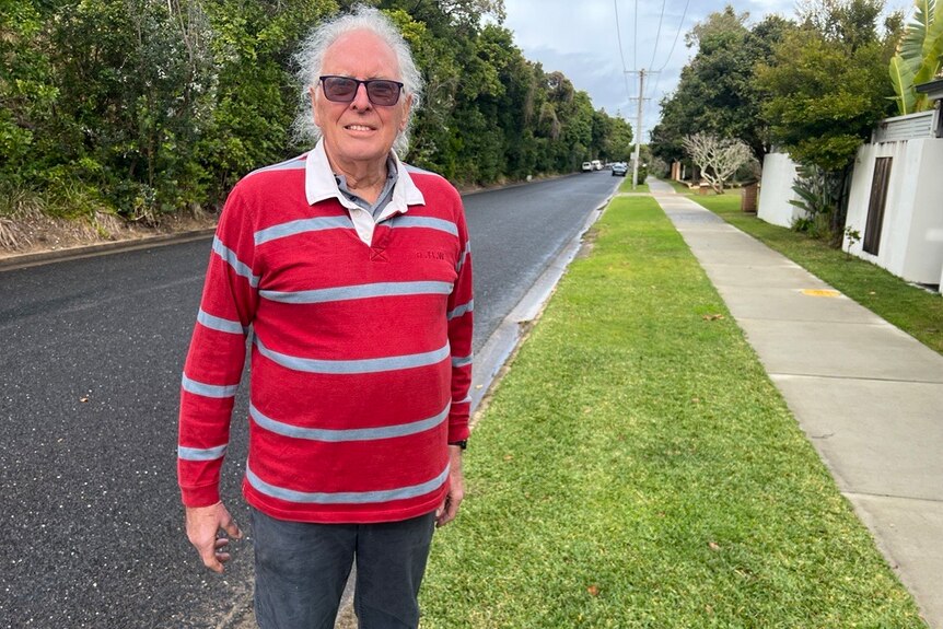 a man standing on a footpath in a suburban street