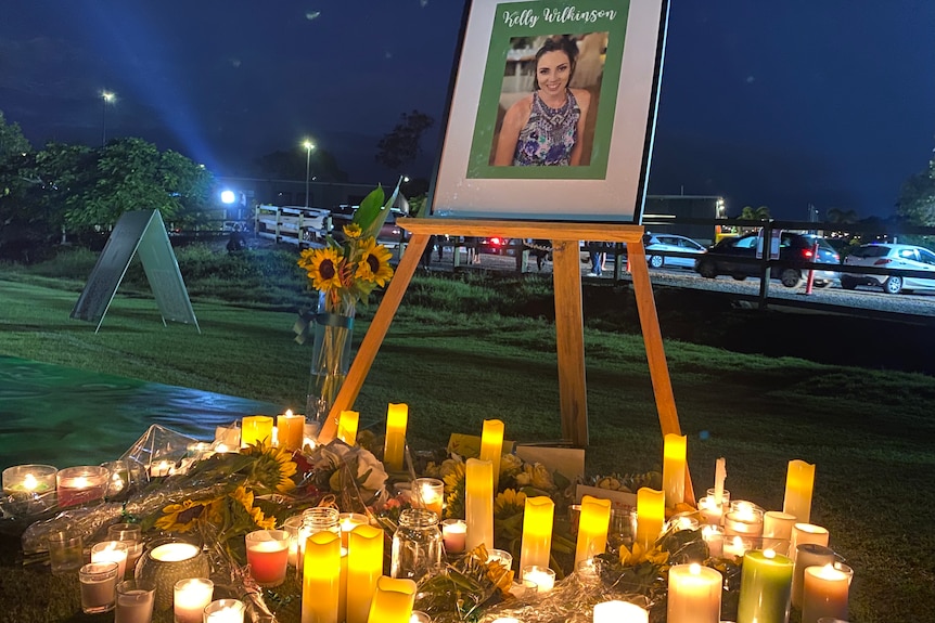 A picture of Kelly with dozens of candles and flowers laid out underneath.