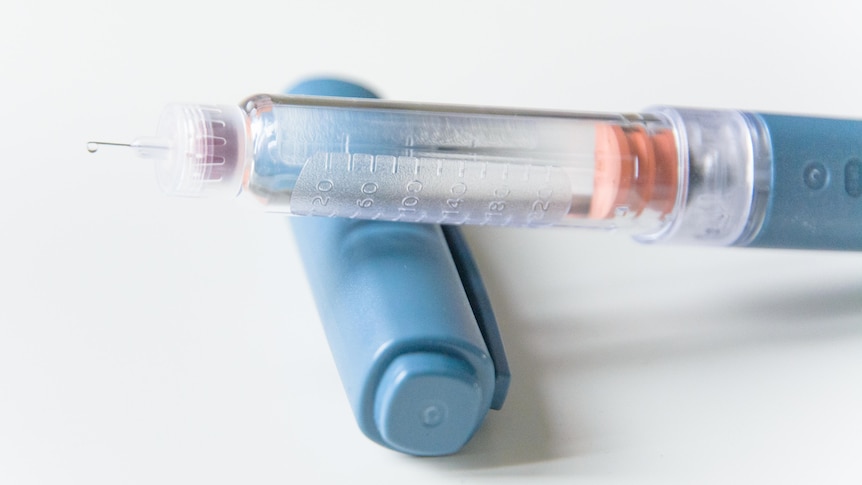 A close-up of a blue injector pen.