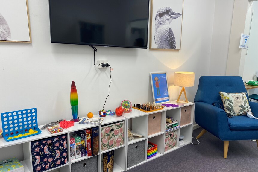 A colourful room with chairs, games, books and a television.