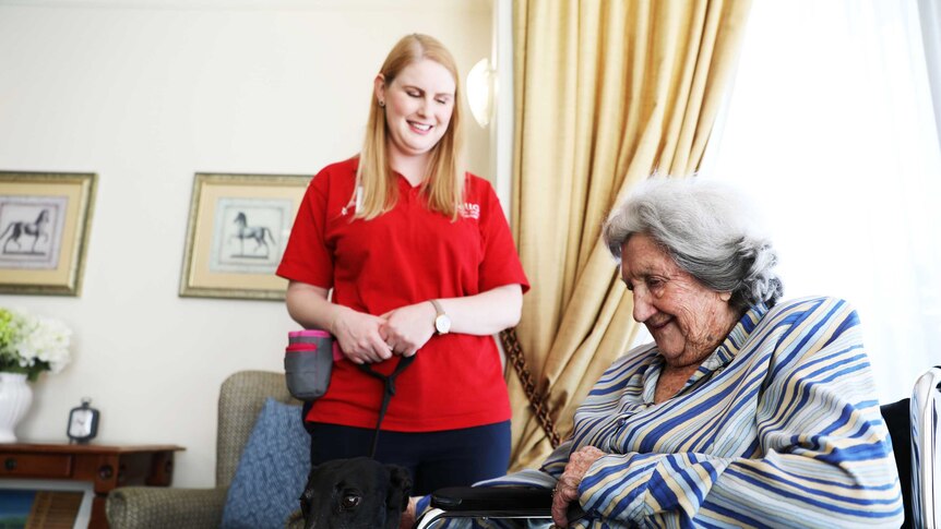 Delta Society volunteer Alana Wade with her greyhound Tiffany, standing with a Jindalee resident.