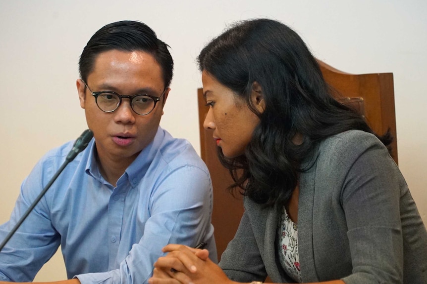 A man speaks to a woman in an Indonesian courtroom.