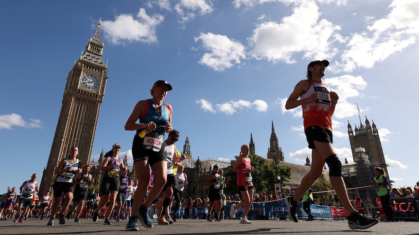 The Big Ben is pictured as people wearing active wear, hats and numbers, are running past it.