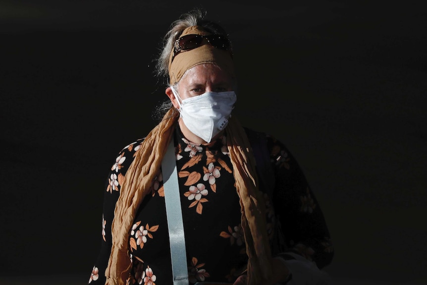 A passenger walks through an airport wearing a mask to help protect against coronavirus.