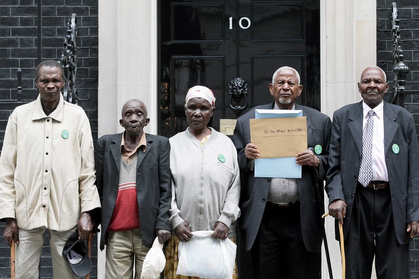 Five people stand in front of a black door with the number 10 sign.