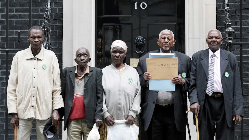 Five people stand in front of a black door with the number 10 sign.