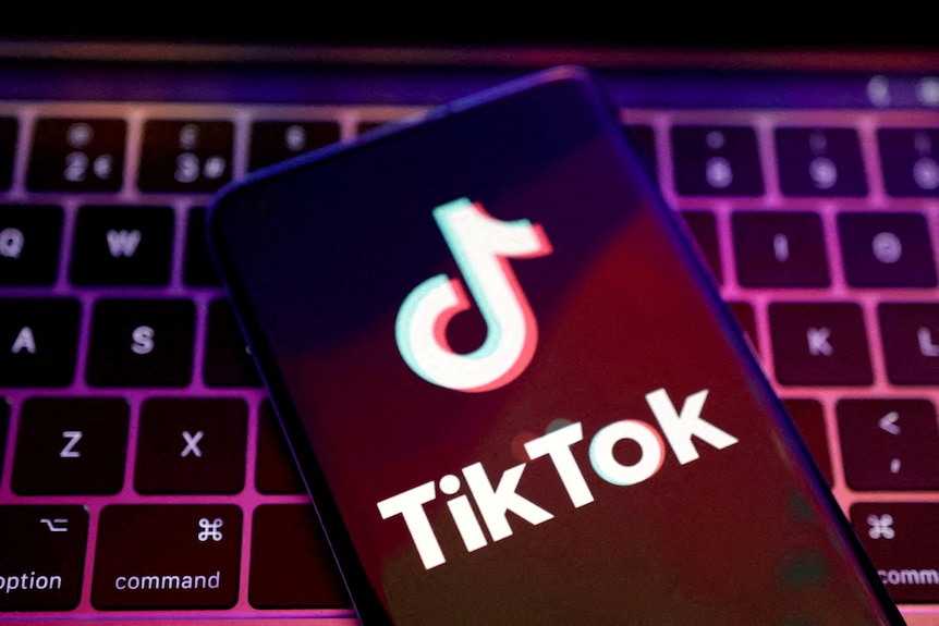 The TikTok logo on a smart phone sitting on top of a computer keyboard
