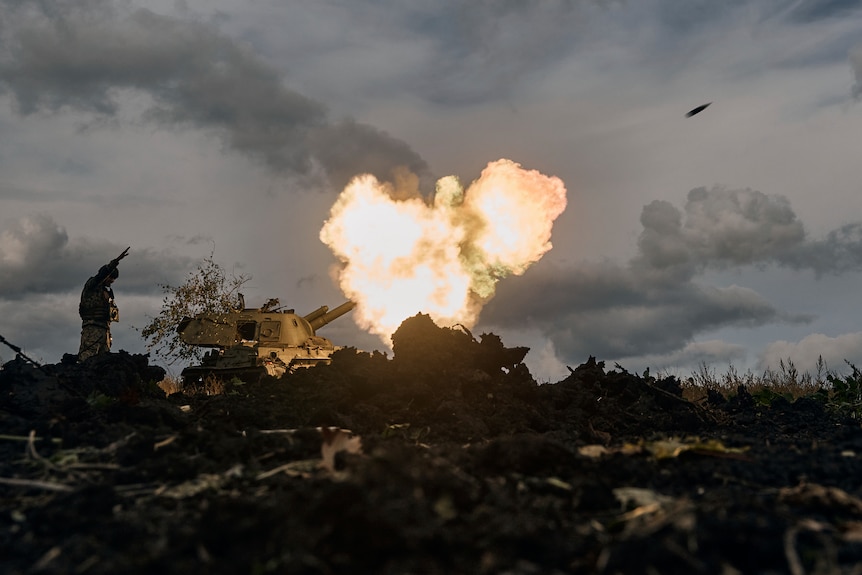 A Ukrainian serviceman reacts as a self-propelled artillery vehicle fires.