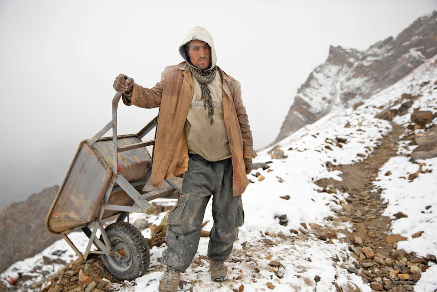 A gem miner sucks in the cold in one of the world's highest altitude mines in the Karakorum Range of northern Pakistan.