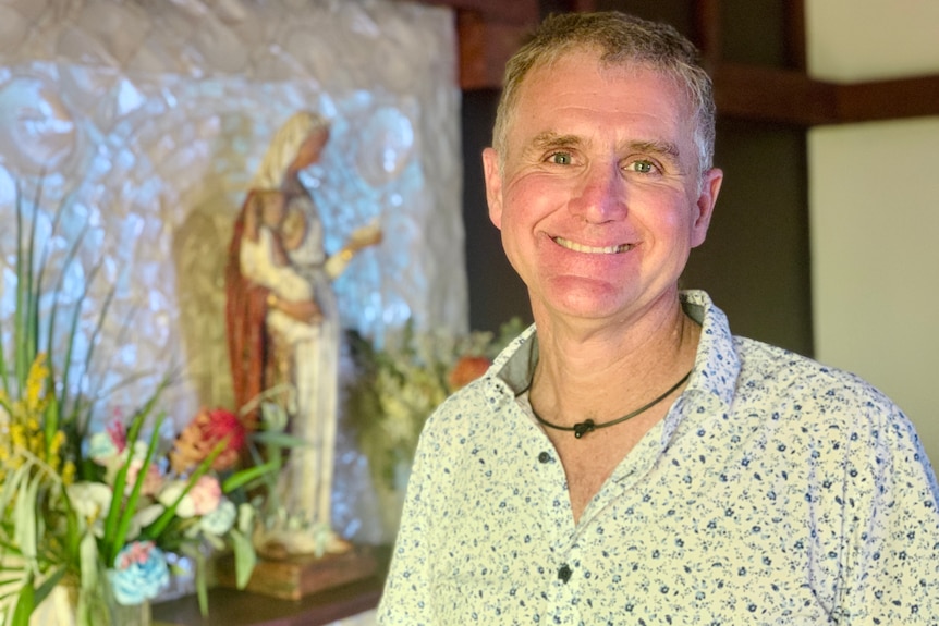 A man with grey hair stands smiling in a church