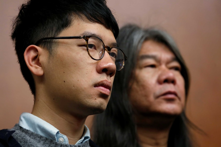 Headshots of Nathan Law and Leung Kwok-hung side-by-side watching a news conference.