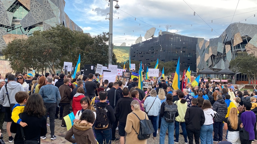 A crowd gathers in Melbourne's Federation Square, carrying placards and Ukrainian flags.