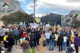 A crowd gathers in Melbourne's Federation Square, carrying placards and Ukrainian flags.