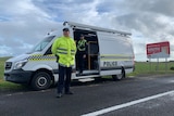 A policeman stands near a van and one inside a van next to a sign about entering South Australia