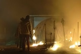 Refugees stand next to burning tents at the Moria refugee camp.