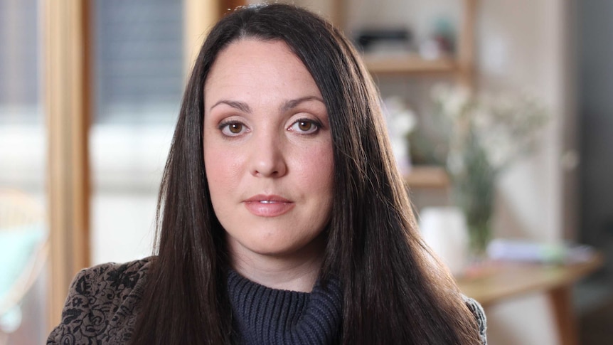 Nina Funnell, wearing black, looks at the camera.