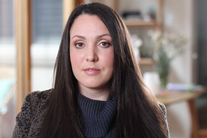 Nina Funnell, wearing black, looks at the camera.