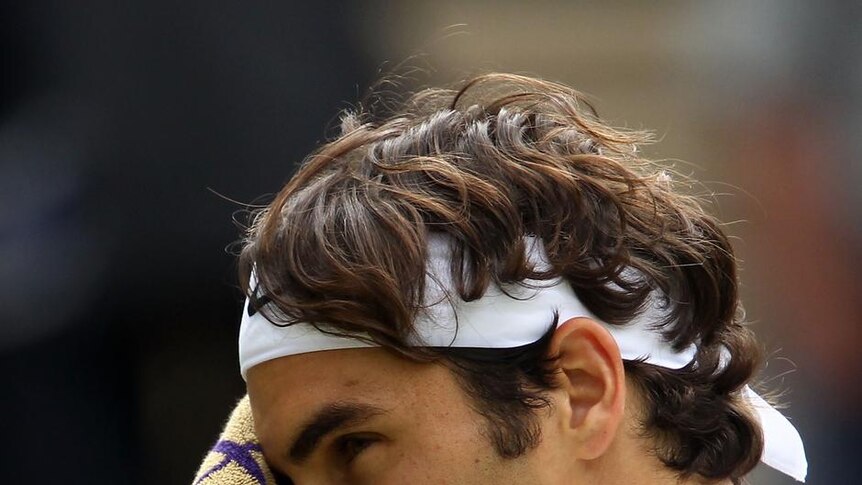 Federer wipes his face with a towel