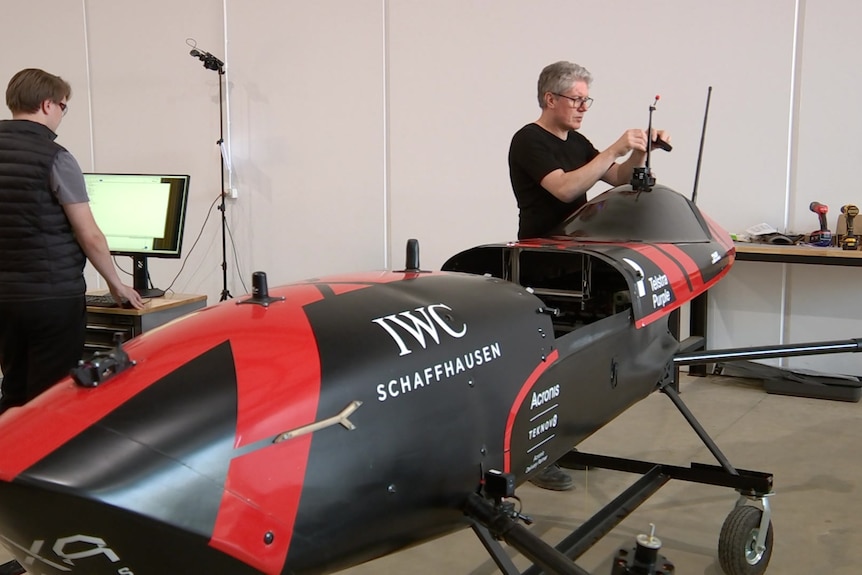 Two men working on a flying car vehicle 