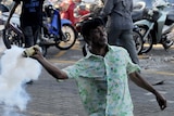 An anti-government protester throws a tear gas canister at police during clashes in the Maldives