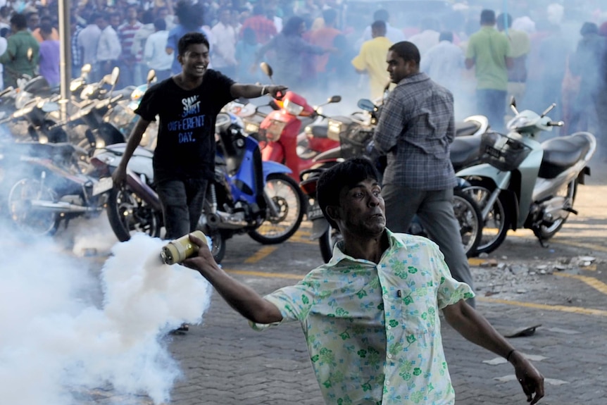 An anti-government protester throws a tear gas canister at police during clashes in the Maldives
