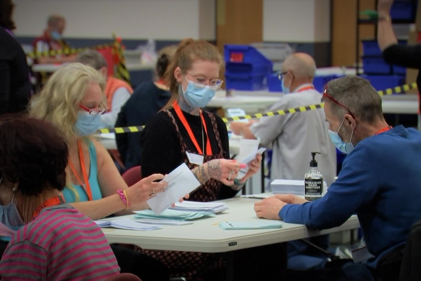 Mask-wearing people counting votes.