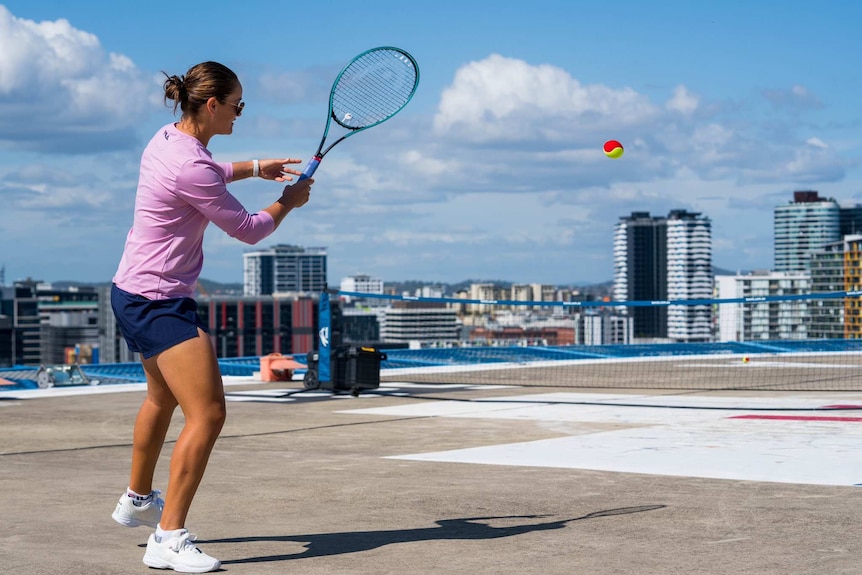 Ash Barty playing tennis on a roof top.