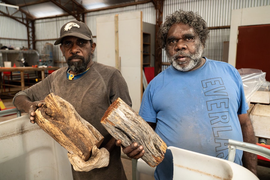Wiston West and Martin Cox holding pieces of fire wood