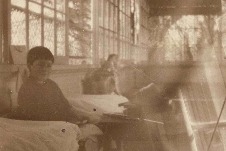 An old photo of a child sitting in the sunroom of the Launceston Infectious Diseases Hospital