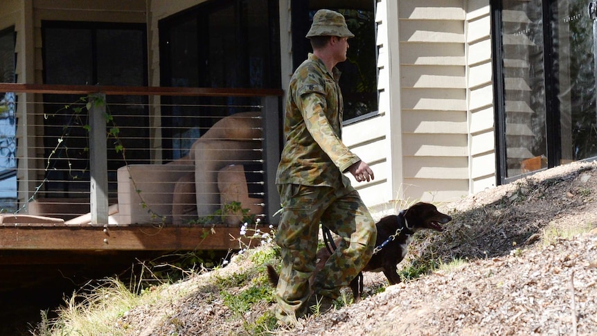 Defence personnel with sniffer dog at Pullenvale property