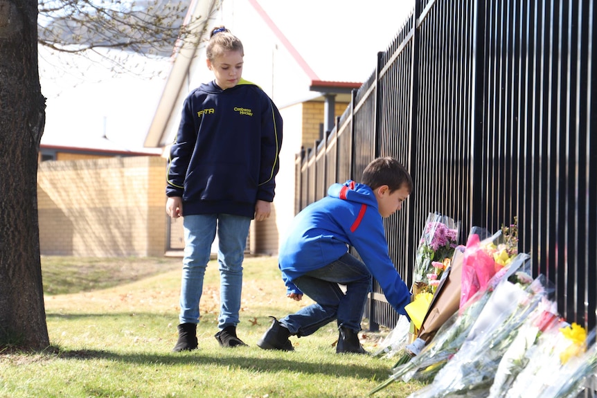 Children lay flowers at a school.