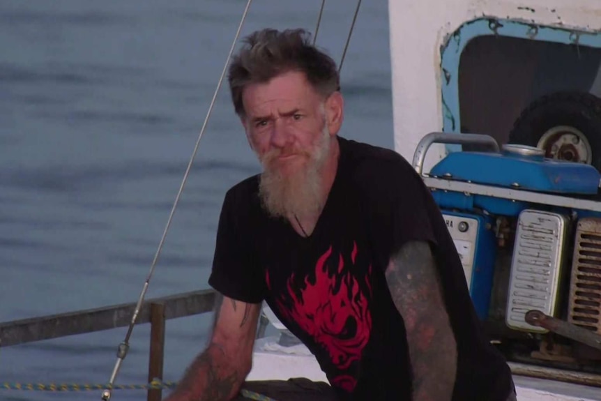 A man with a beard standing on a boat deck