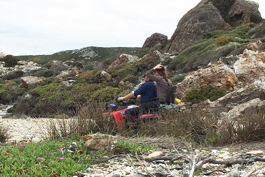 A couple riding a quad bike on a coast line.