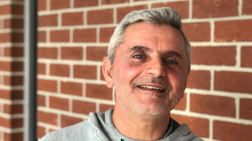 A man in front of a brick wall