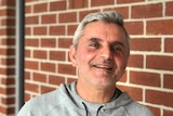 A man in front of a brick wall