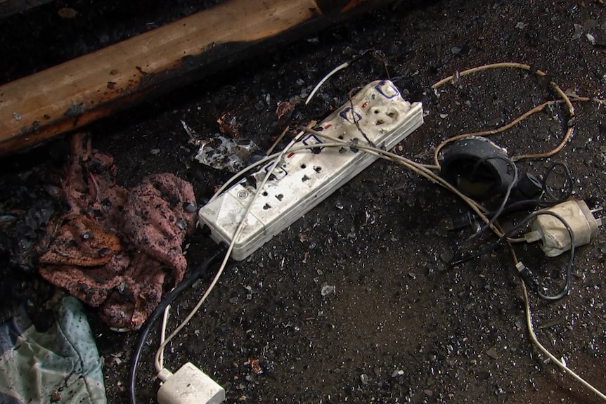 A blackened power board covered in debris from a fire.
