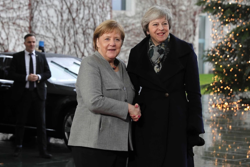 British Prime Minister Theresa May smiles at the cameras as she is greeted by German Chancellor Angela Merkel