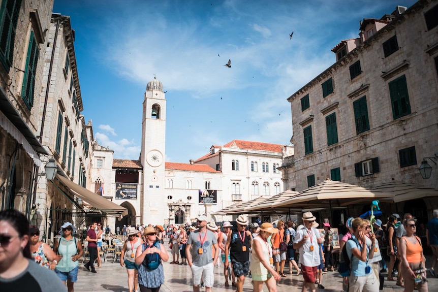 Tourists walking through an old town in Sunshine in Croatia.