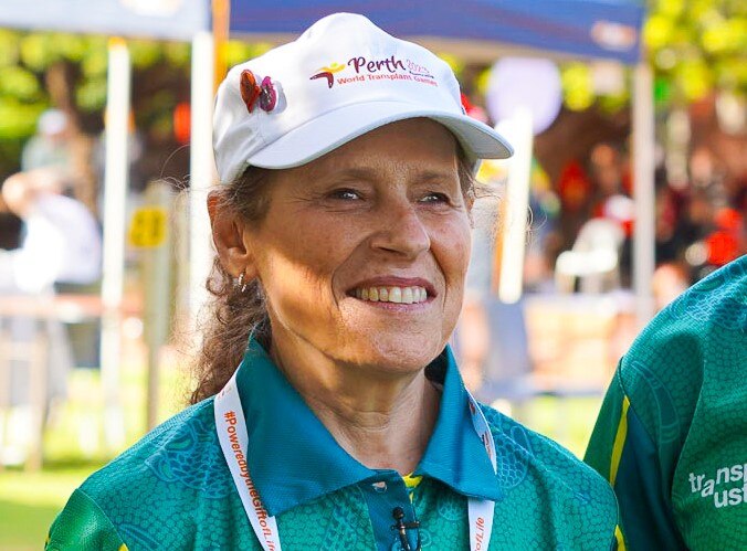 Lynette wearing green and gold and smiles while looking directly at the camera