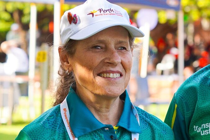 Lynette wearing green and gold and smiles while looking directly at the camera