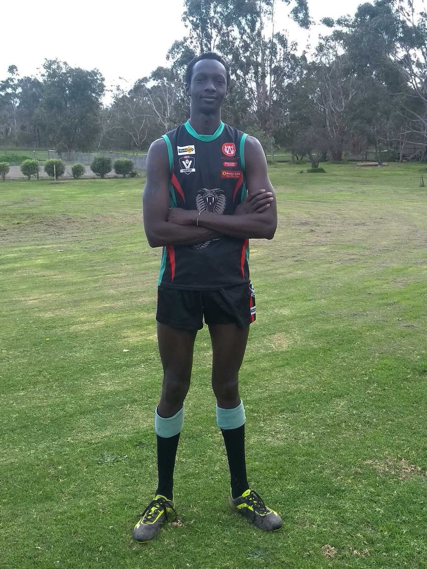 Lado Alphonse is dressed in his Cora Lynn Cobras team uniform as he stands in a garden.