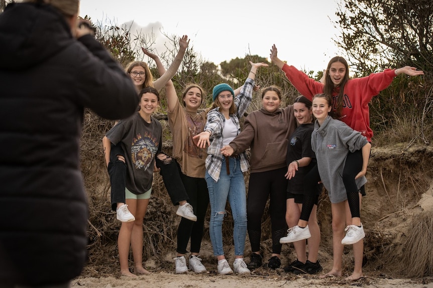 A group of students have their picture taken on a beach