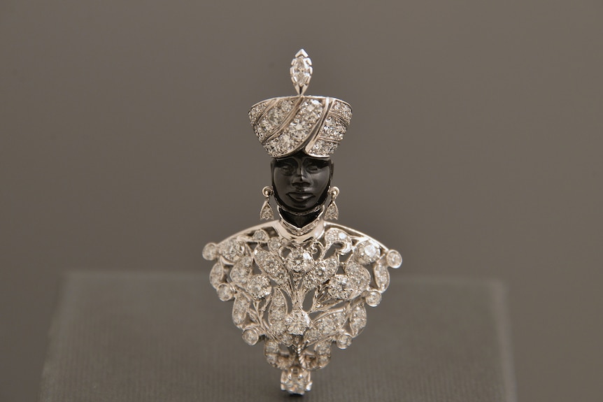 An brooch of a black man wearing a diamond turban, necklace and earrings