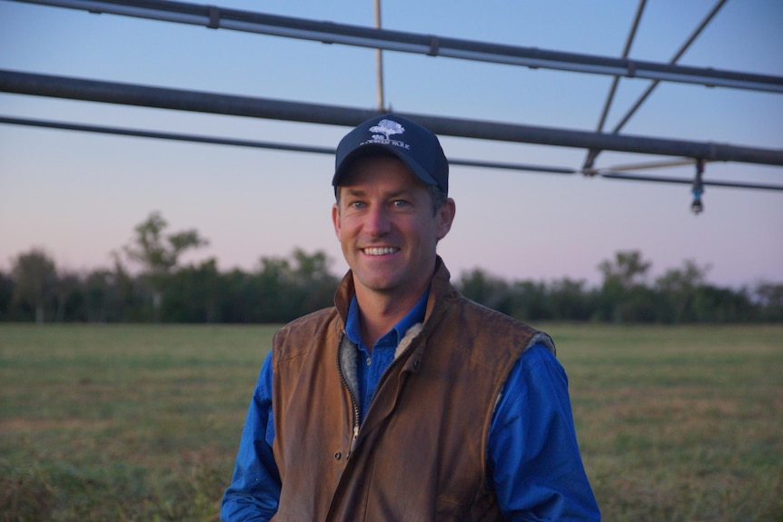 Image of a man smiling in front of green paddocks.