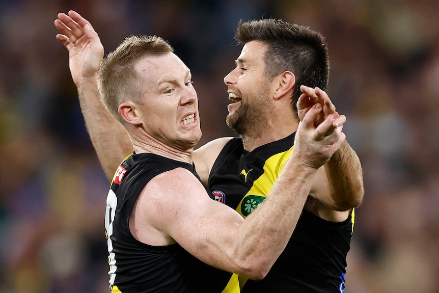 Two Richmond AFL players embrace as they celebrate a goal against Geelong.