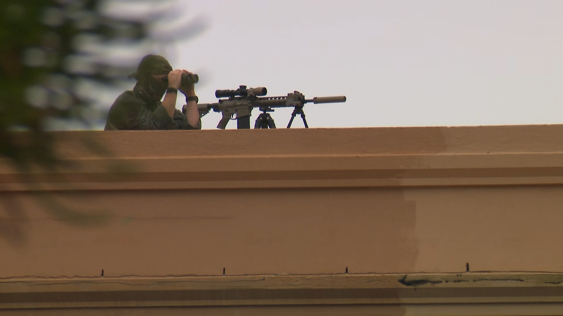 Un francotirador en un tejado mira a través de binoculares.