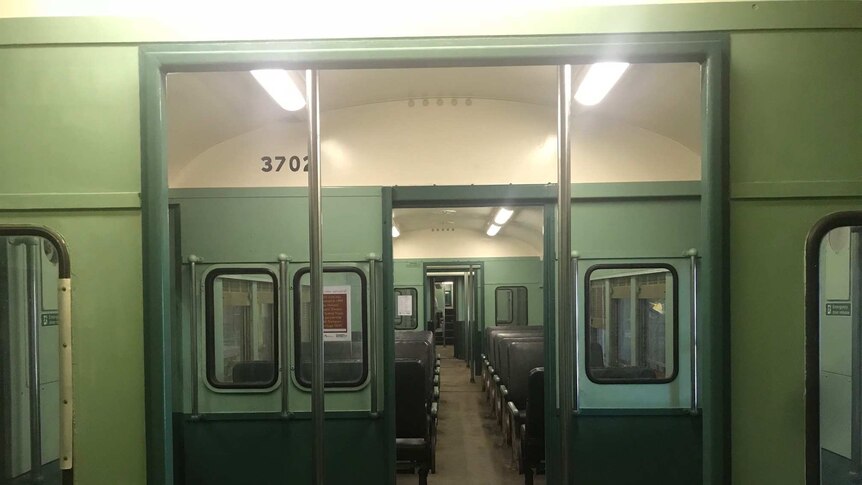The inside of a disused historic train painted green.