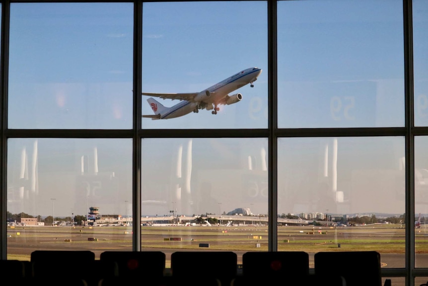 Image of a plane taking off seen from within an empty airport terminal.