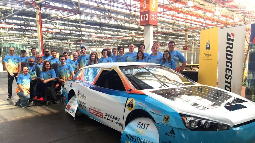 A solar-powered car with a group of students.